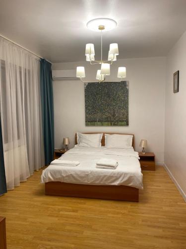 a bedroom with a large white bed and a chandelier at DATIVO HOUSE in Mamaia Sat/Năvodari