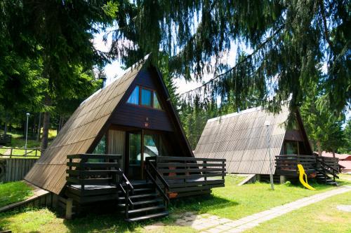 a small house with a thatched roof sitting under a tree at Romantica Forest Guest House in Dospat