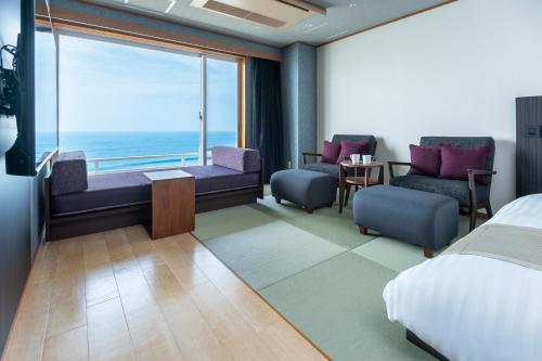a hotel room with a bedroom with a view of the ocean at Kamogawa Grand Hotel in Kamogawa