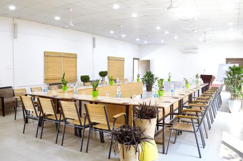 a large room with a long table with chairs and potted plants at Savana Lake Resort in Nashik