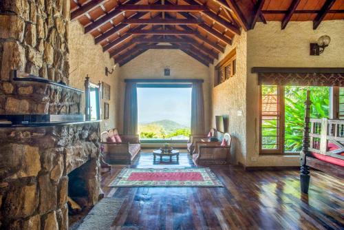 a large living room with a large stone fireplace at Urvinkaan - An Estate Hotel Chikmagalur in Chikmagalur