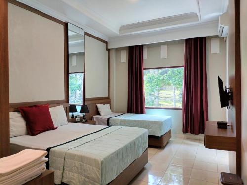 a hotel room with two beds and a television at Hotel Indria in Bukittinggi