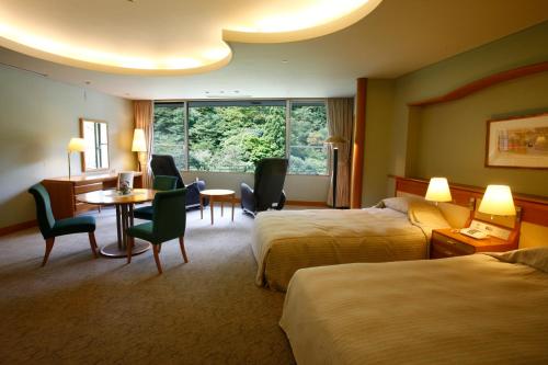 a hotel room with two beds and a table and chairs at Arima Onsen Gekkoen Korokan in Kobe