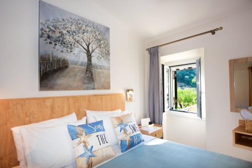 a bedroom with a bed with a painting on the wall at Nina's House by CorfuEscapes in Doukádes