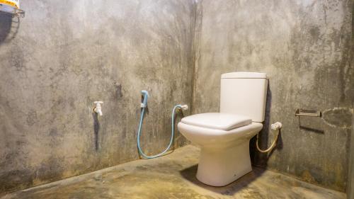 a bathroom with a toilet with a hose on the wall at Golden Rainbow Guest House in Dambulla