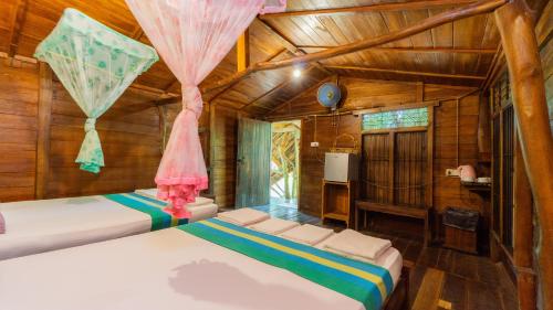 two beds in a room with wooden walls at Golden Rainbow Guest House in Dambulla