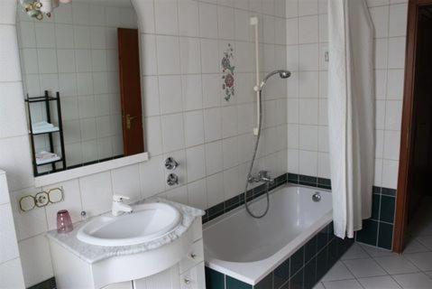 a bathroom with a sink and a tub and a mirror at Hotel B&S in Waghäusel