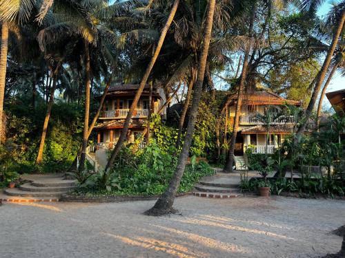 a resort with palm trees in front of a building at Anahata Retreat Beach Front Resort in Mandrem