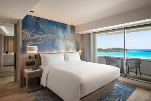a bedroom with a large bed and a large window at Courtyard by Marriott Okinawa Resort in Nago