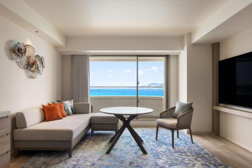 a living room with a couch and a table and a window at Courtyard by Marriott Okinawa Resort in Nago