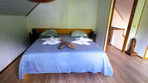 a bed in a room with two towels on it at Chalet Familiale Vue Mer et Coucher de Soleil Moorea in Moorea