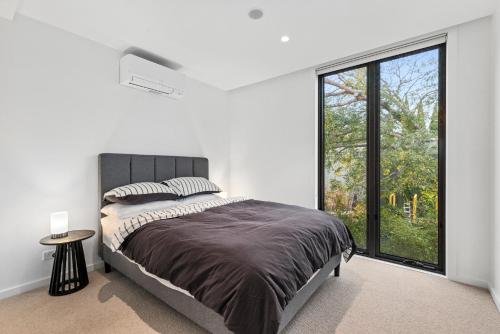 a bedroom with a large bed and a large window at Brighton Beach Terrace in Melbourne