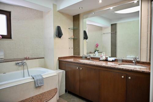 a bathroom with two sinks and a tub and a large mirror at Erato Superior Suite in Kremasti