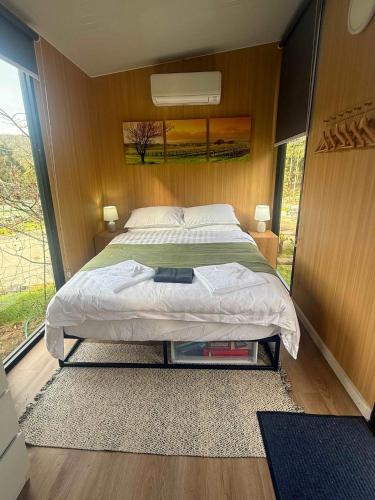 a bedroom with a bed and a large window at Gum Tree by Tiny Away in Dixons Creek
