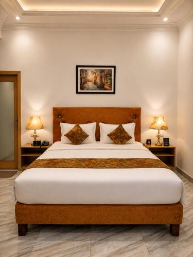 a bedroom with a large bed with two lamps at Lawrence View Hotel, Lahore in Lahore