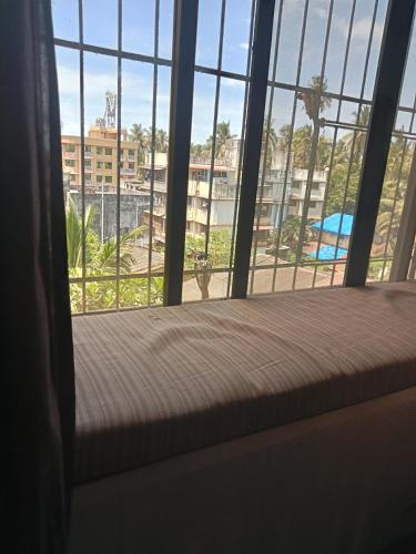 a window with a bed looking out at a city at Grantley -Beach hotel Alibag in Alībāg