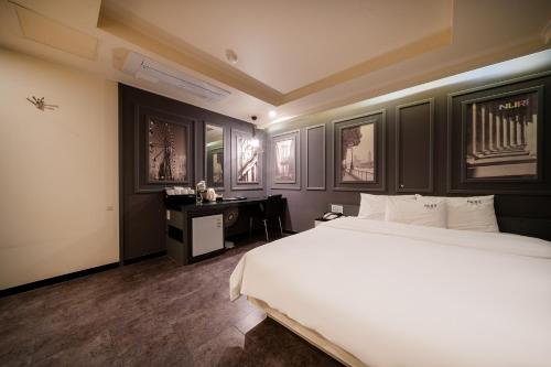 a bedroom with a large white bed and a desk at Busan Gwangalli Nuri Hotel in Busan