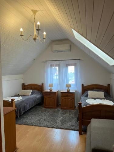 a attic bedroom with two beds and a chandelier at U Krba in Nitra