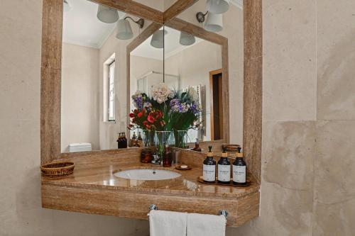 a bathroom with a sink with a mirror and flowers at Rocha's House - Setúbal in Setubal