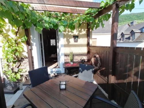a patio with a wooden table and chairs on a deck at Moselfrische in Zell an der Mosel