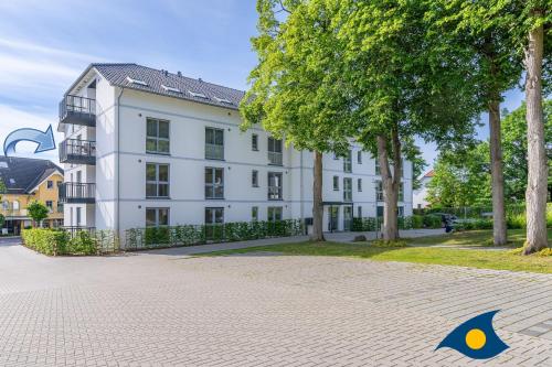 a large white building with trees in front of it at Bernsteinquartier Whg 11 "Inselglück" in Kölpinsee
