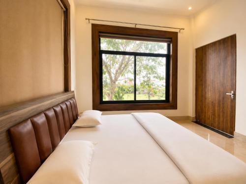a large bed in a room with a window at Hotel Vasant - Premium Hotel in Gajraula - All AC Rooms with Restaurant - Free Wi-fi & Parking - Banquet in Gajraula
