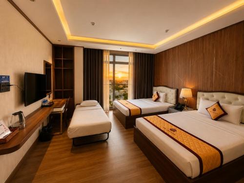 a hotel room with two beds and a desk at Thảo Ngân Pleiku Hotel in Pleiku