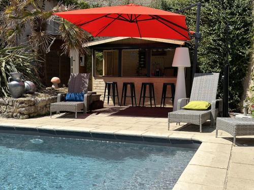 a patio with chairs and an umbrella next to a pool at LA MAISON JEROBOAM in Saint-Estèphe