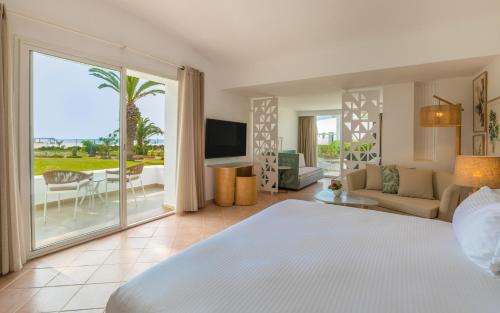 a bedroom with a bed and a living room at Steigenberger Marhaba Thalasso Hammamet in Hammamet