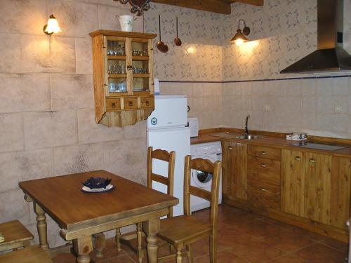 a kitchen with a table and a white refrigerator at El Porma in Villanueva del Condado