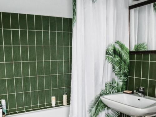 a green tiled bathroom with a sink and a shower curtain at FLC Rooms in Rødby