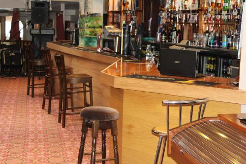 a bar with wooden stools and a bunch of bottles at Middlegate Hotel in Pembroke