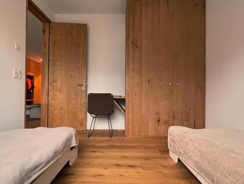 a bedroom with two beds and a desk and a chair at Casa Rok in Flims