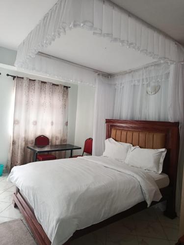 a bedroom with a large white bed and a table at J & J Olosho Hotel in Kiserian