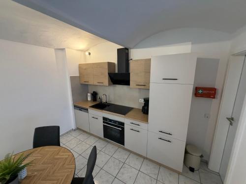 a small kitchen with white cabinets and a table at Auszeit am Brunnen in Mendig