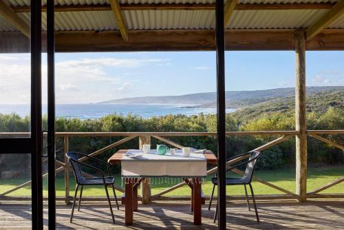 a table and chairs on a porch with a view of the ocean at Chandlers Smiths Beach Villas in Yallingup