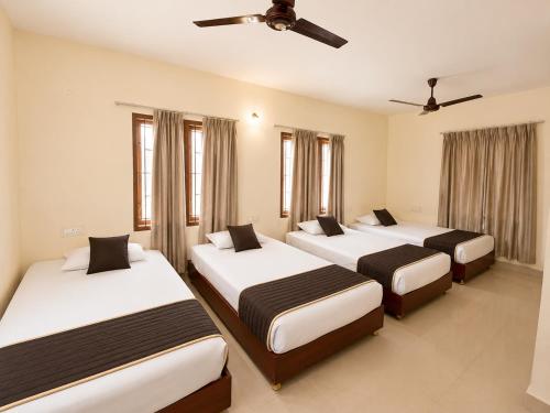 three beds in a room with windows at BKR Resort in Kuttālam