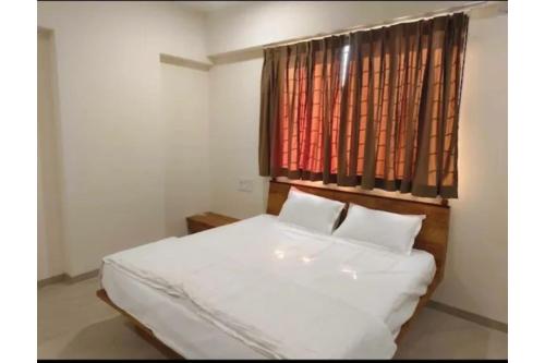 a bedroom with a white bed and a window at FabHotel Bhagyashri Executive in Nashik