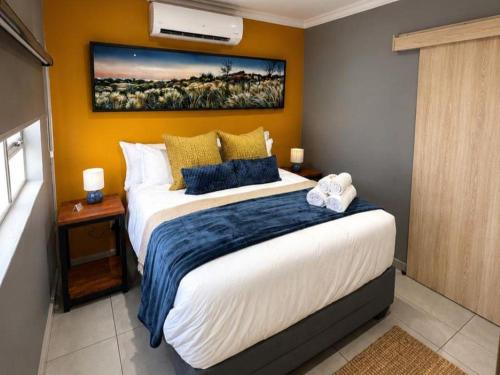 a bedroom with a large bed with a painting on the wall at Kairos Guesthouse in Thabazimbi