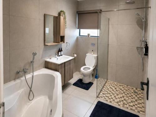 a bathroom with a tub and a toilet and a sink at Kairos Guesthouse in Thabazimbi
