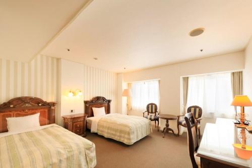 a hotel room with two beds and a desk at Hirosaki Park Hotel in Hirosaki