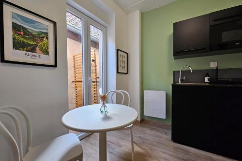 a kitchen with a white table and chairs in a room at Studio cocooning à 5km du centre de Strasbourg in Schiltigheim