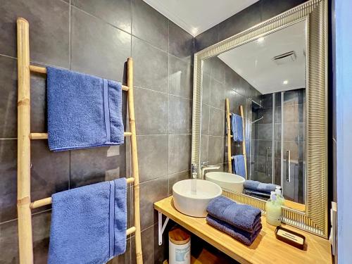a bathroom with a sink and a mirror and blue towels at COCON HYPER CENTRE-VILLE TOUT CONFORT (8) in Ajaccio