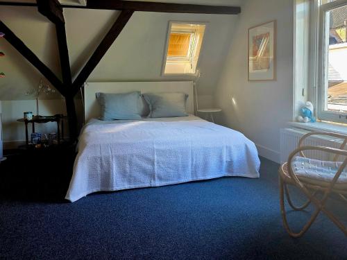 a bedroom with a bed with a white bedspread and two windows at Large Historical Apartment & Canal Terrace in Utrecht