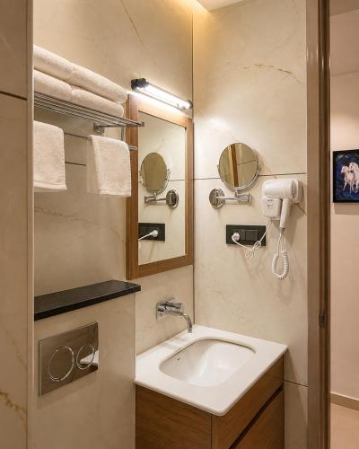 a bathroom with a sink and a mirror at Hotel Hanata Kochi in Cochin