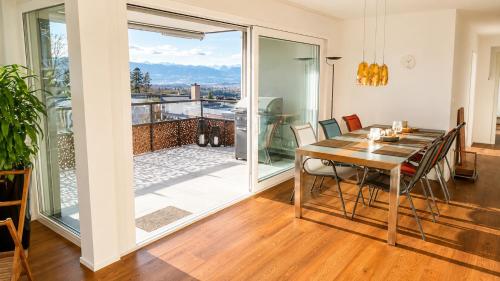 a dining room with a table and a balcony at Swiss Horizon - Mythenblick - Modern 100m2 mit Alpenblick und Terrassen in Hinwil