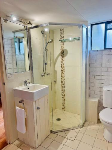 a bathroom with a shower and a sink and a toilet at Garden Studio - Tranquil Forest Retreat in Currumbin Valley