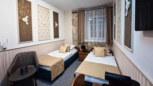 a hotel room with two beds and a chair at Cieszyński by Imperis Hotels in Cieszyn