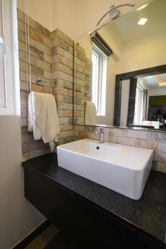a bathroom with a white sink and a mirror at Lumino Winter Castle, Munnar in Pooppara