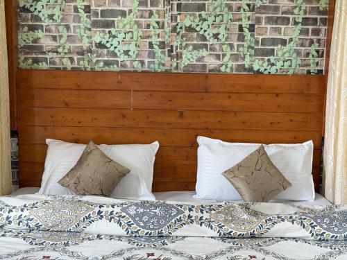 a bed with white pillows and a brick wall at The Sanmit Stay Kasauli by Splendid Retreat Hotels in Kasauli